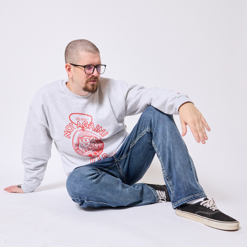 Man wearing a gray sweatshirt with a graphic design and text, sitting on a white background